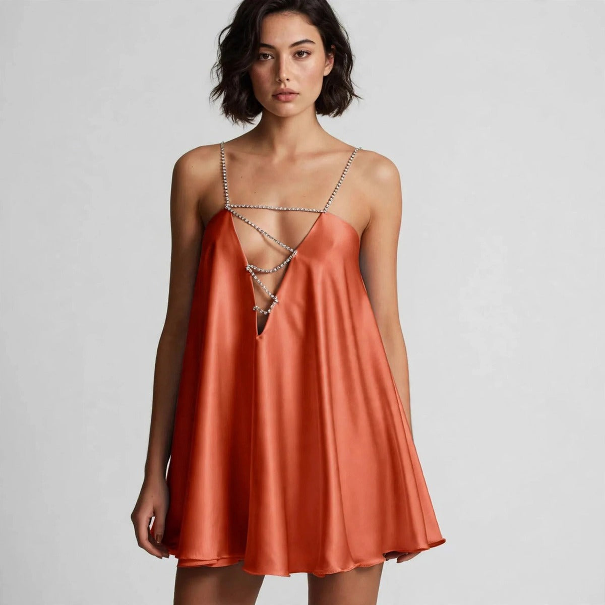 Woman wearing orange rhinestone mini dress with chain-strap plunge neckline