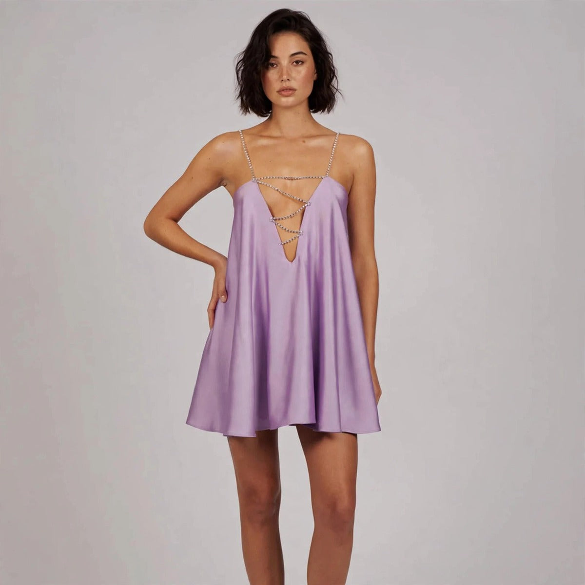Woman posing with hand on hip in a lavender satin slip mini dress with thin straps and chain lace-up front.