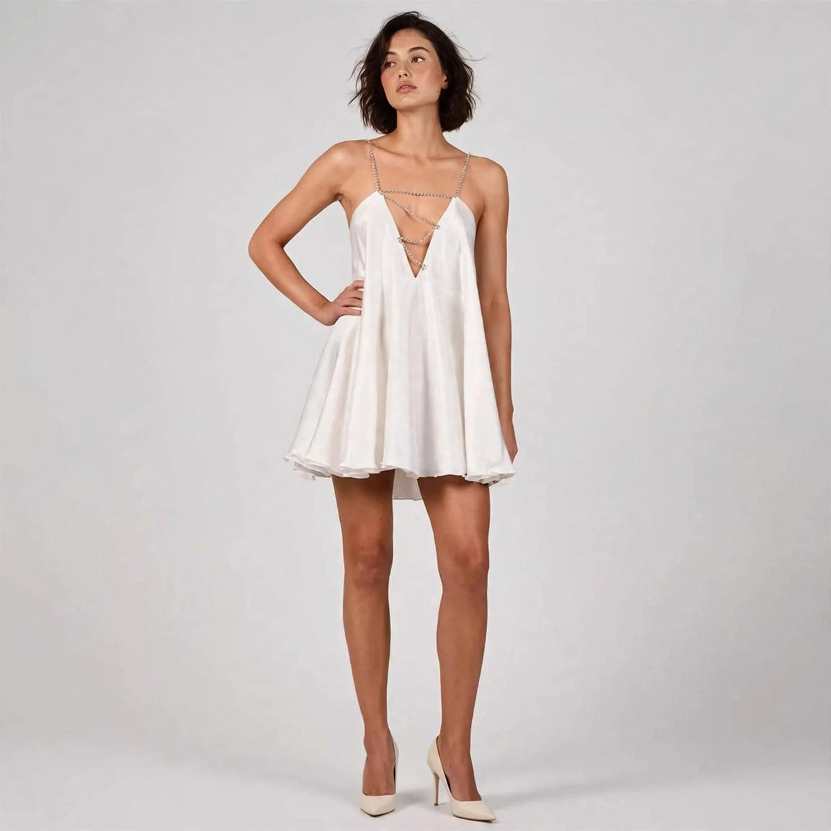 Model wearing white rhinestone mini dress in a fashion editorial pose