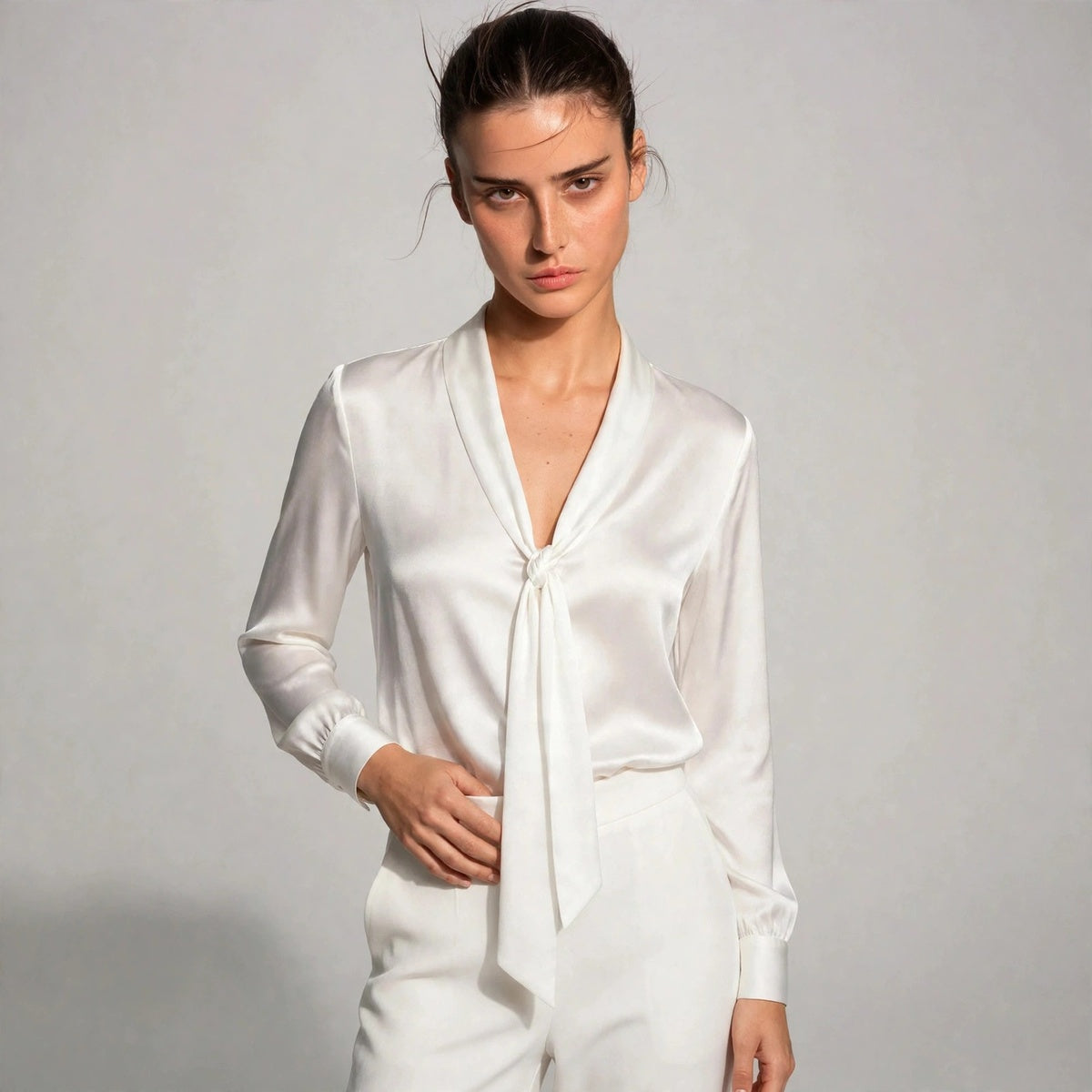 Woman wearing white satin tie-neck blouse with knotted front detail