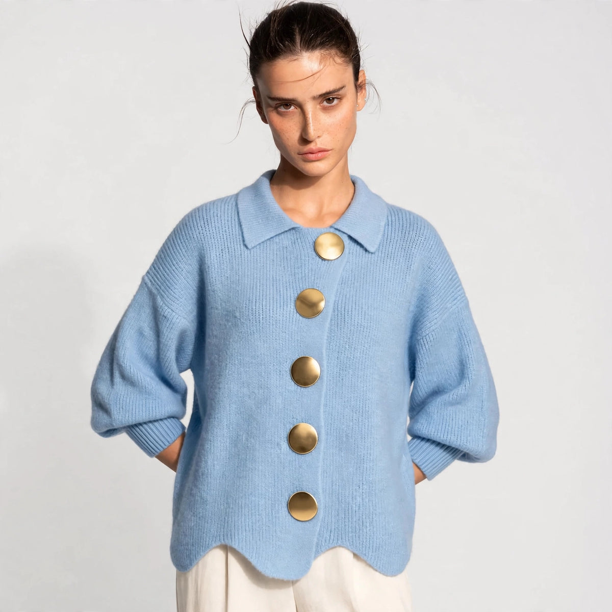 Woman wearing sky blue gold-button knit cardigan with lantern sleeves, front view