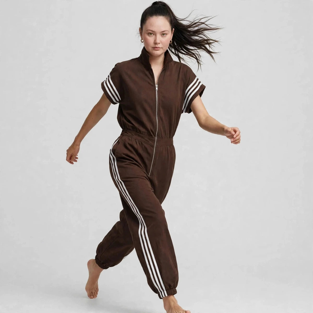 Three-quarter view of brown sporty stripe zip-front jumpsuit with white stripes