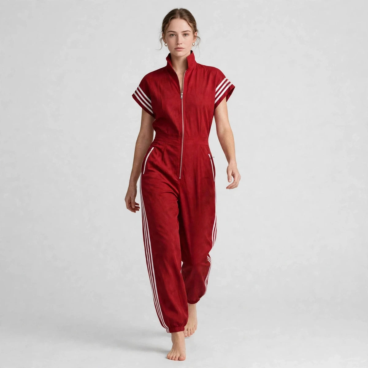 Model walking in red sporty stripe zip-front jumpsuit with windblown hair, front view