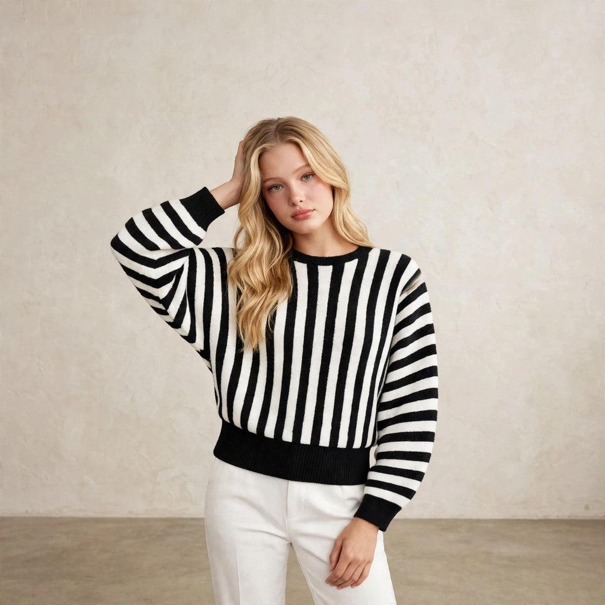 Women's black striped knit sweater, hand in hair editorial pose
