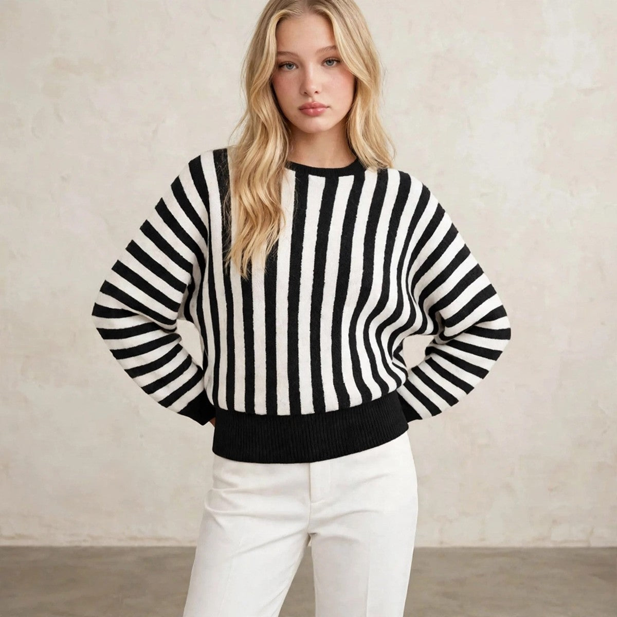 Women's black and white vertical striped sweater, hands behind hips pose