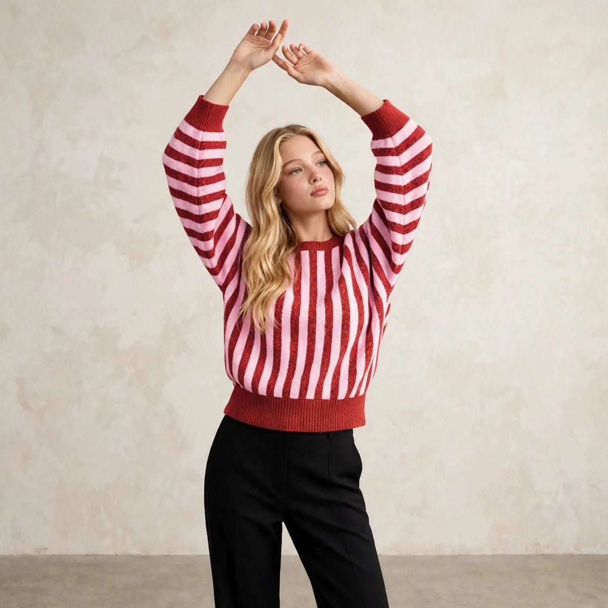 Women's deep red striped knit sweater, editorial pose with arms raised