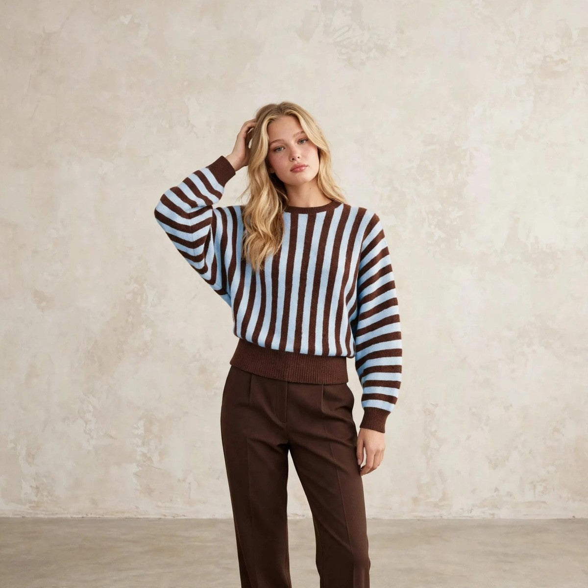 Women's light blue striped knit sweater, hand in hair editorial pose