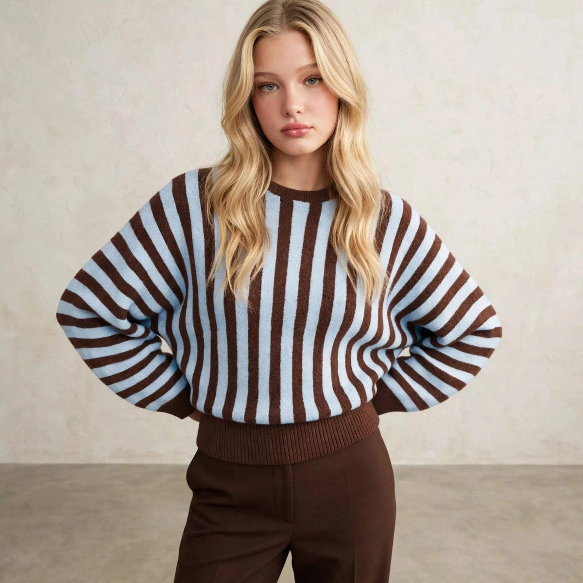 Women's light blue and brown vertical striped sweater, hands behind hips pose