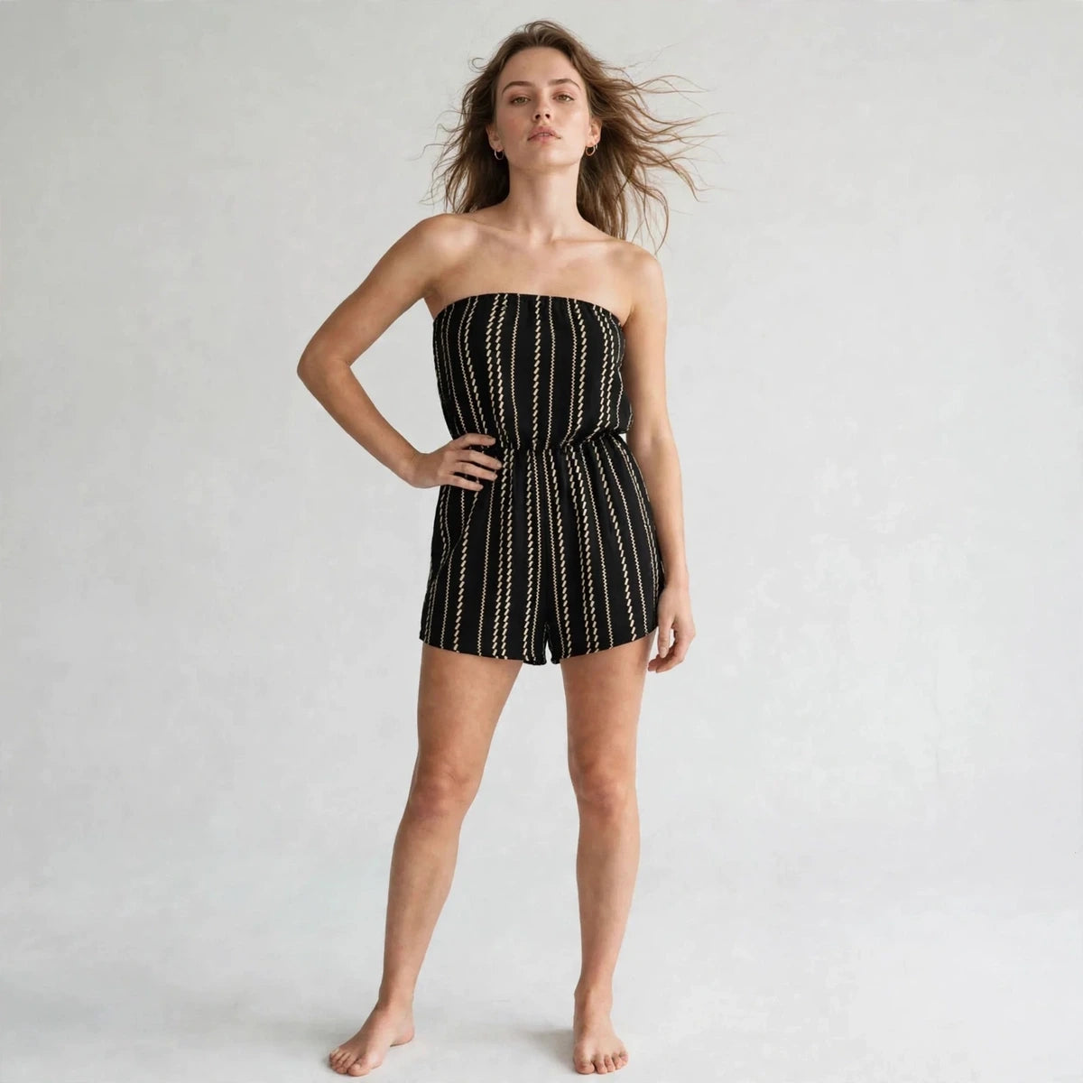 Woman wearing black striped strapless tube romper with elastic waist, front view