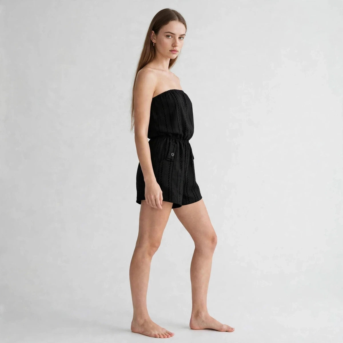 Side view of black striped strapless tube romper with elastic waist