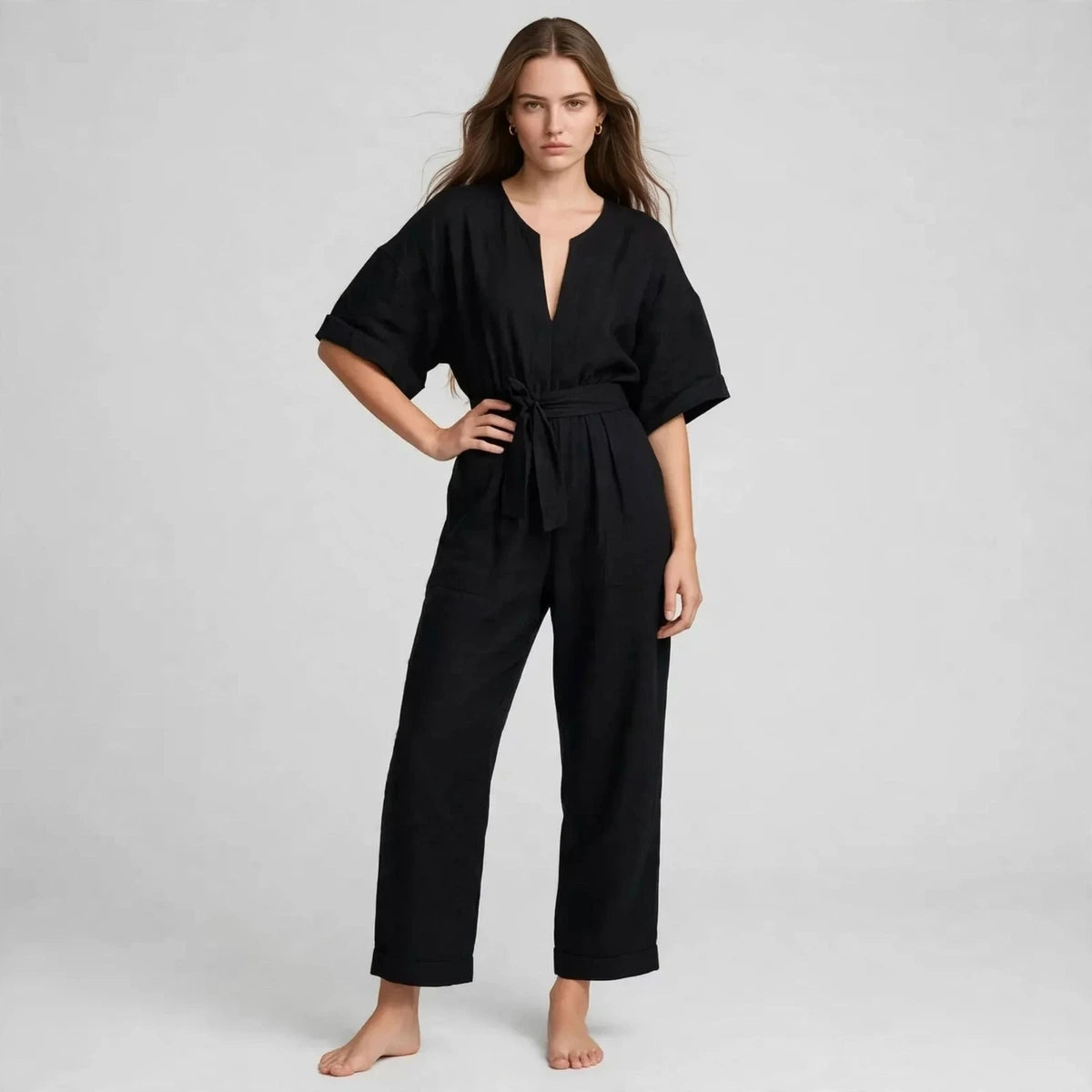 Woman wearing black V-neck tie waist jumpsuit with short sleeves, front view