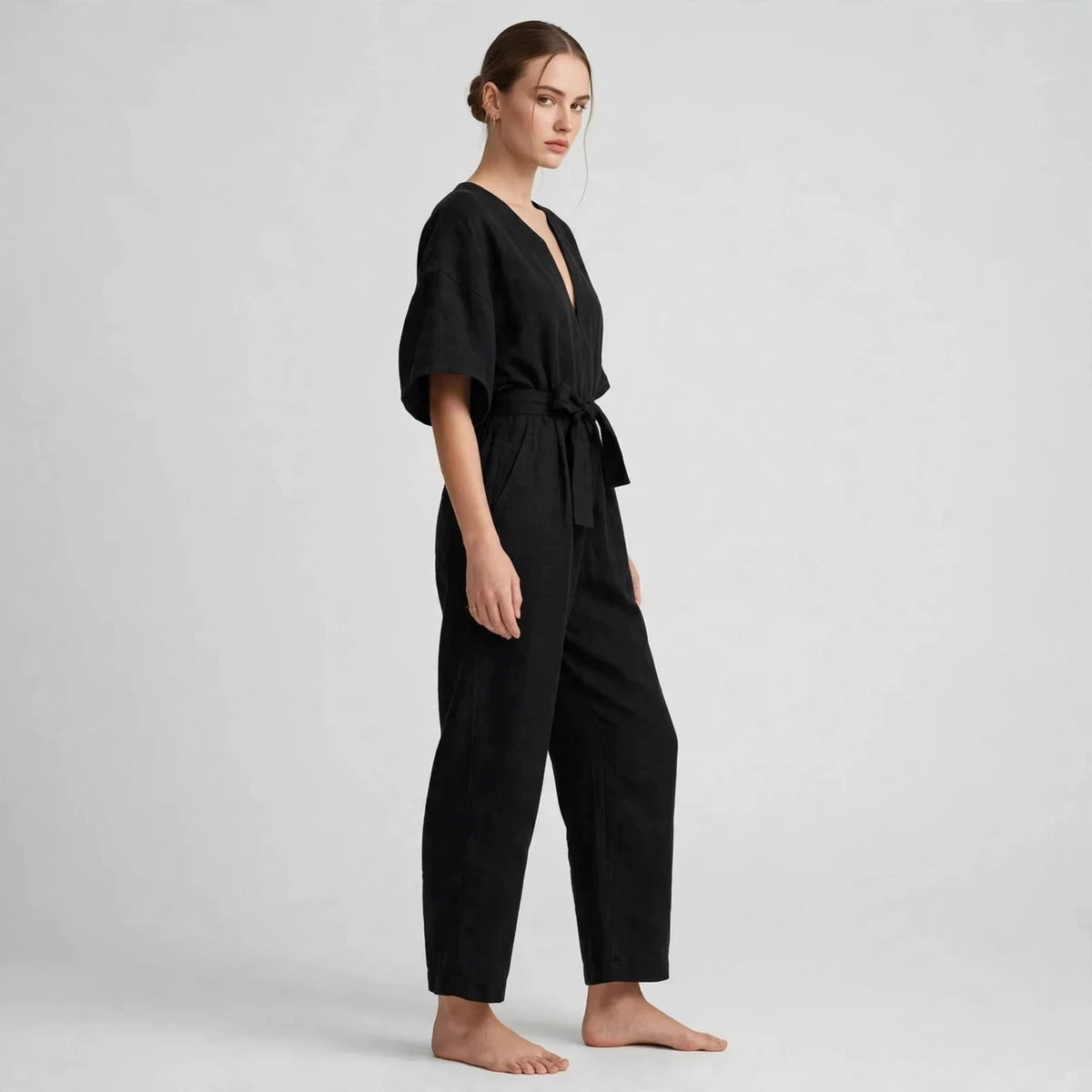 Side view of black V-neck tie waist jumpsuit with tied belt