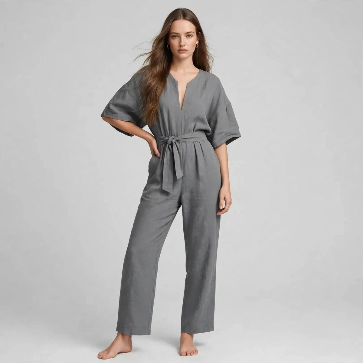 Woman wearing gray V-neck tie waist jumpsuit with short sleeves, front view