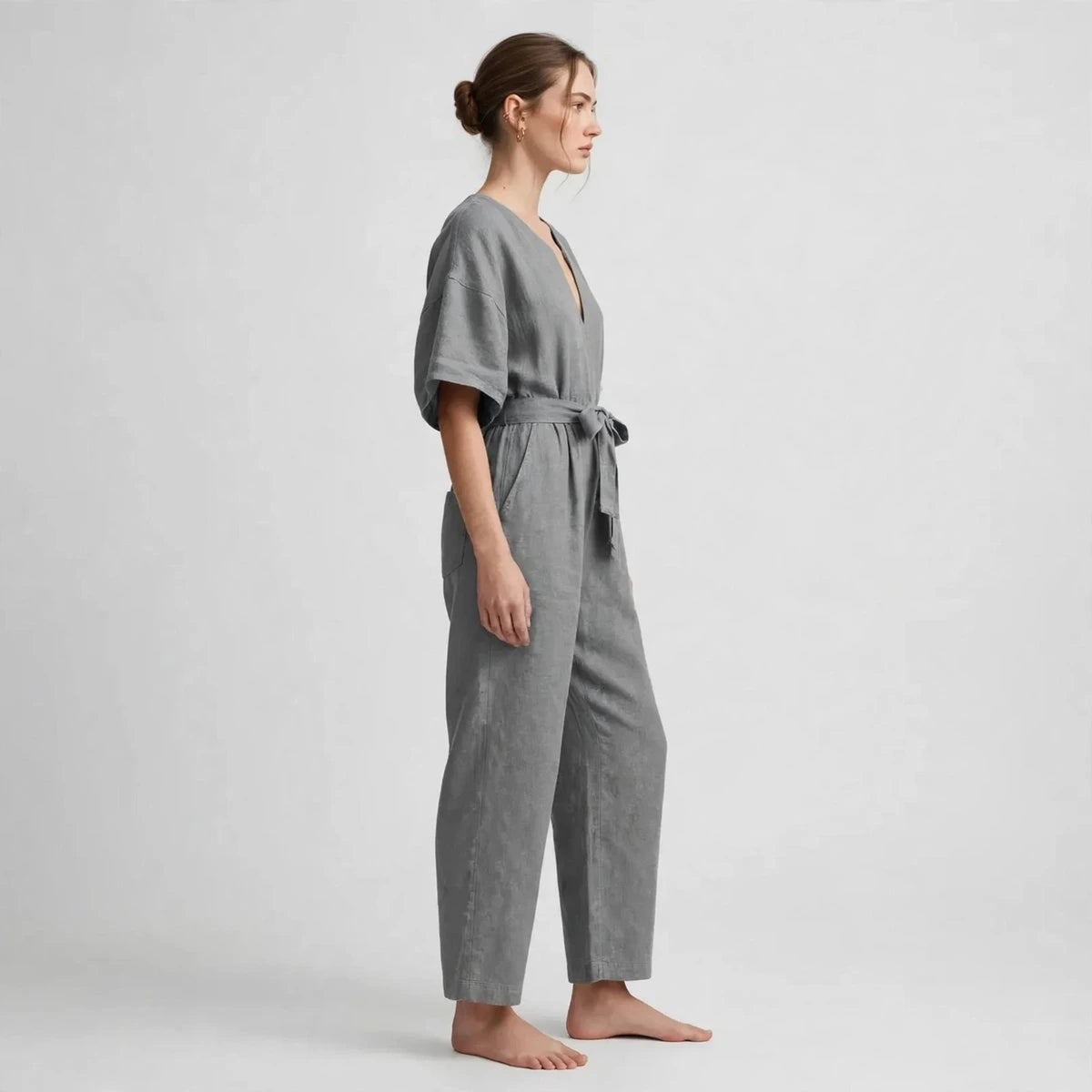 Side view of gray V-neck tie waist jumpsuit with tied belt