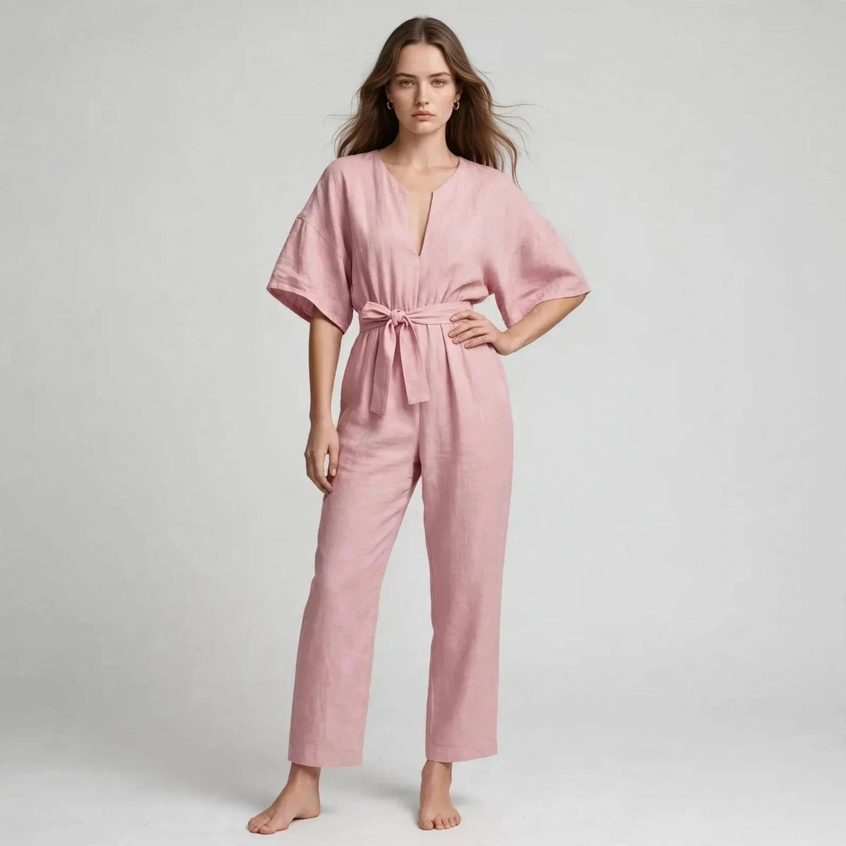 Woman wearing pink V-neck tie waist jumpsuit with short sleeves, front view