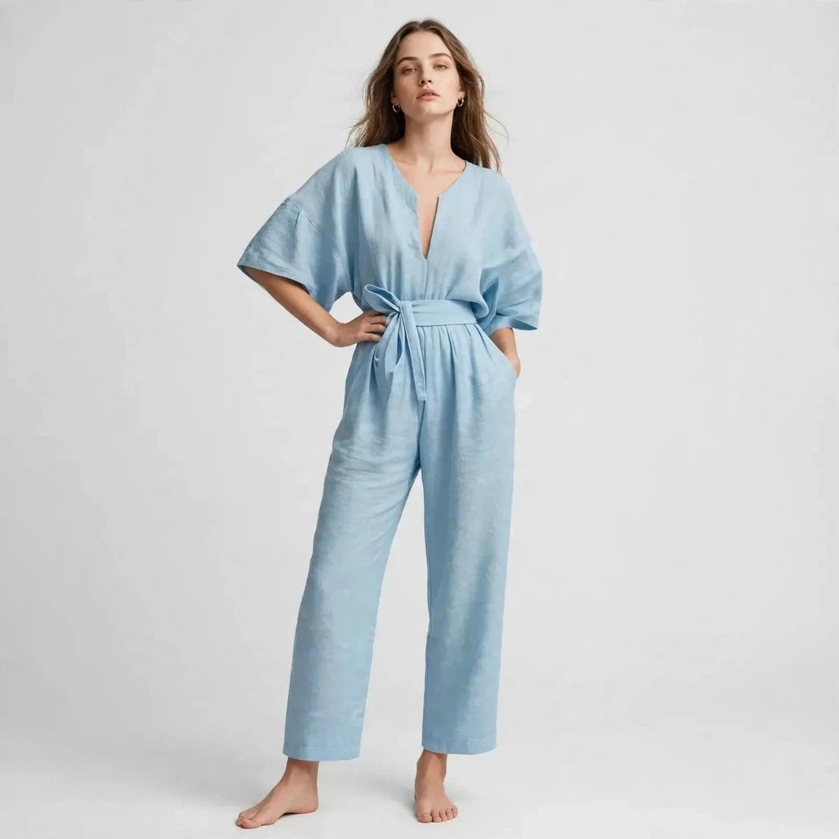Woman wearing sky blue V-neck tie waist jumpsuit with short sleeves, front view