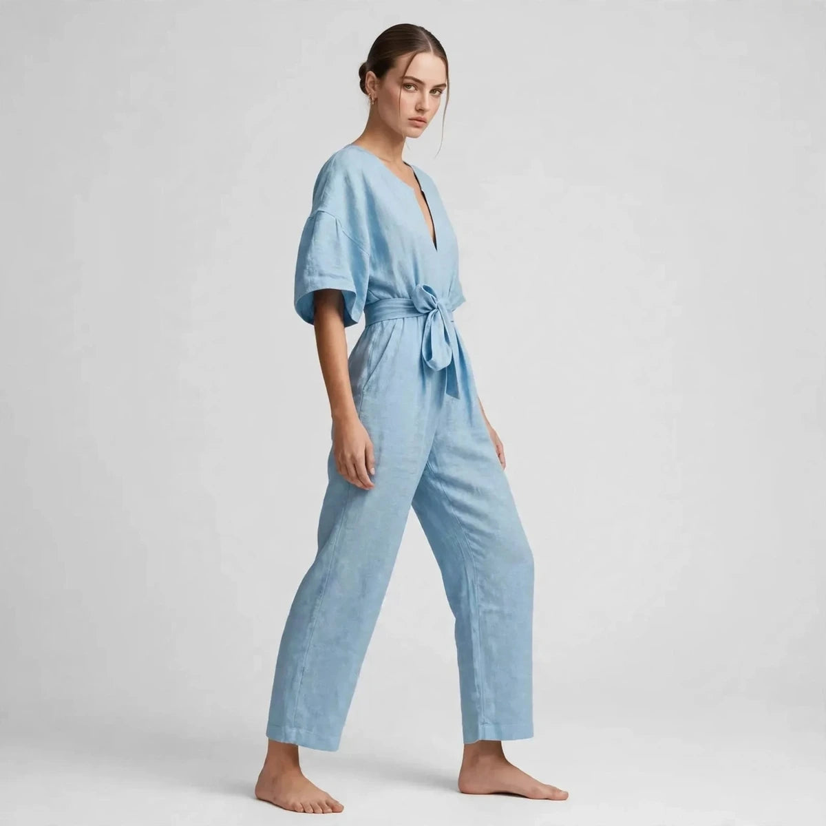Side view of sky blue V-neck tie waist jumpsuit with tied belt