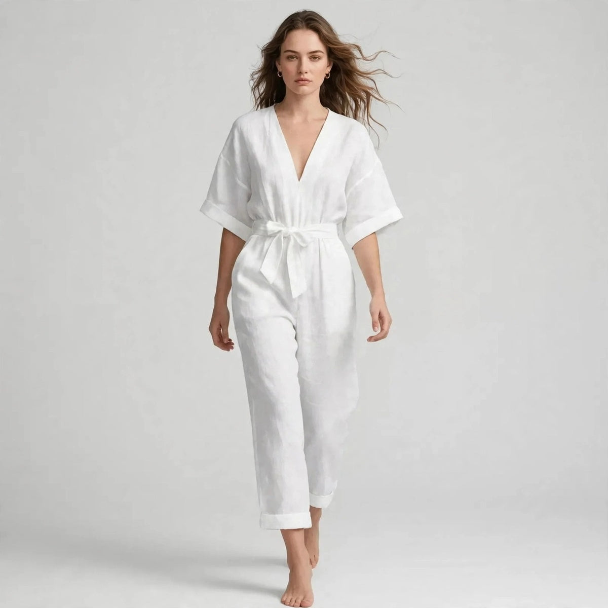 Woman wearing white V-neck tie waist jumpsuit with short sleeves, front view