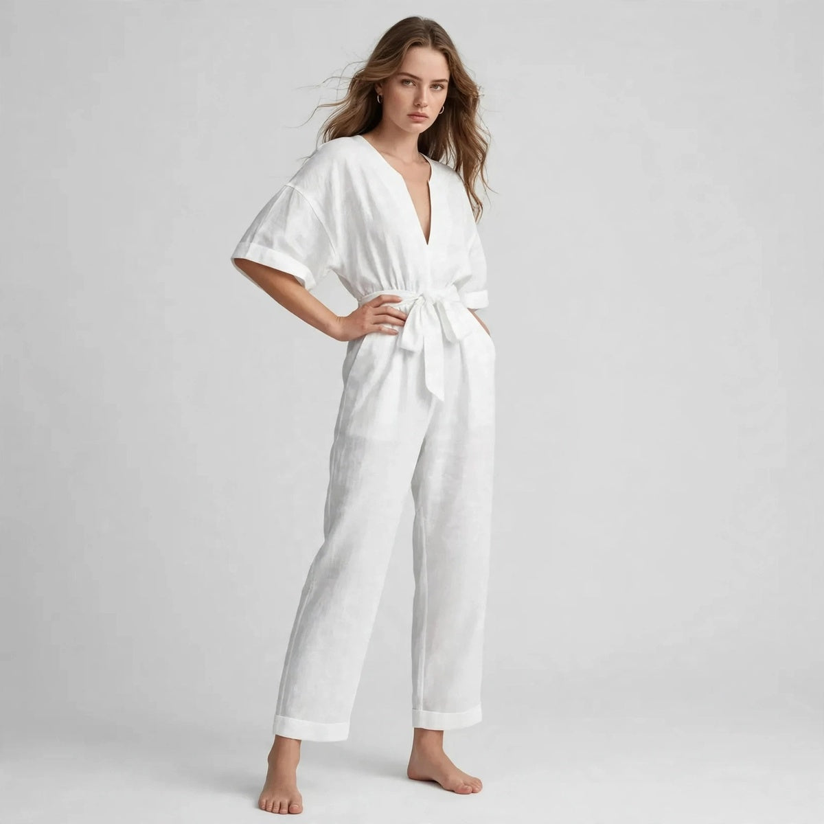 Model wearing white V-neck tie waist jumpsuit, three-quarter view