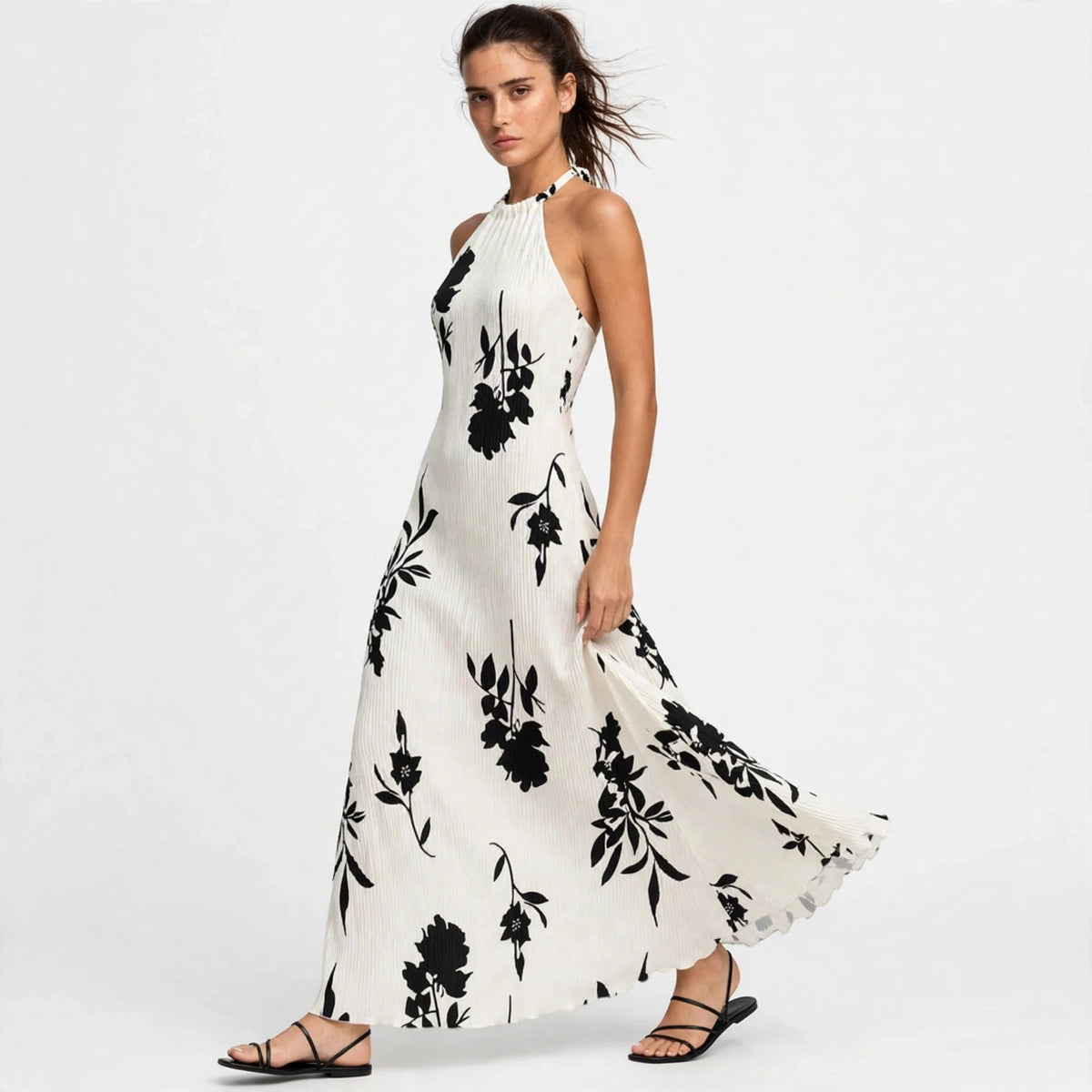 Three-quarter view of white floral halter maxi dress with flowing skirt