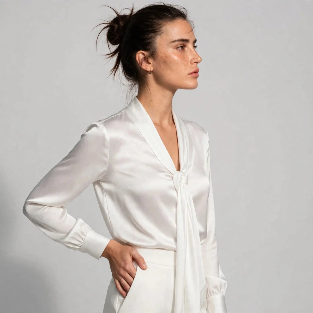 Side view of white satin tie-neck blouse showing knotted tie detail