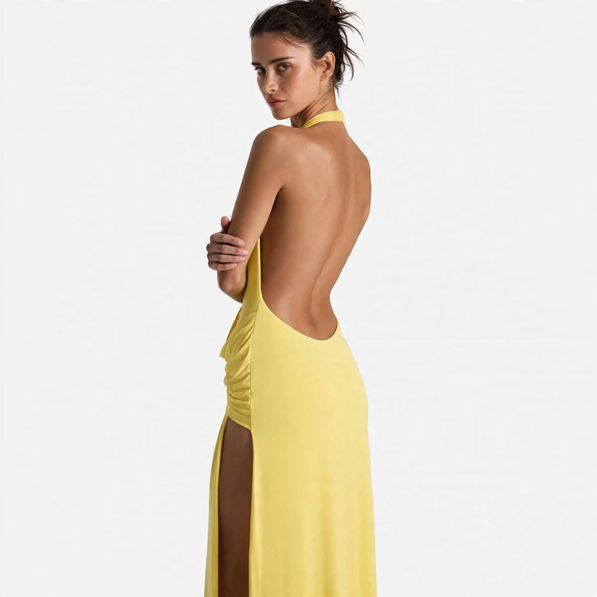 Back view of yellow backless halter maxi dress showing open back and thigh slit