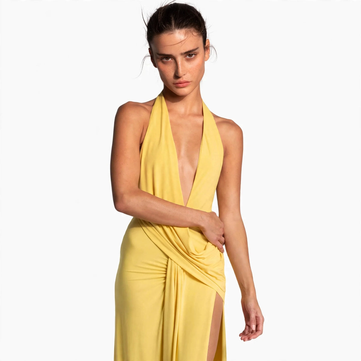 Woman wearing yellow backless halter maxi dress with draped cowl neckline