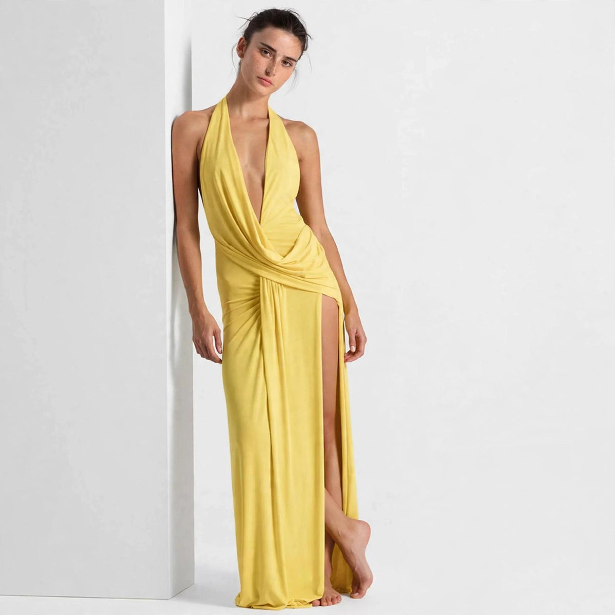 Front view of yellow backless halter maxi dress with draped bodice and thigh slit