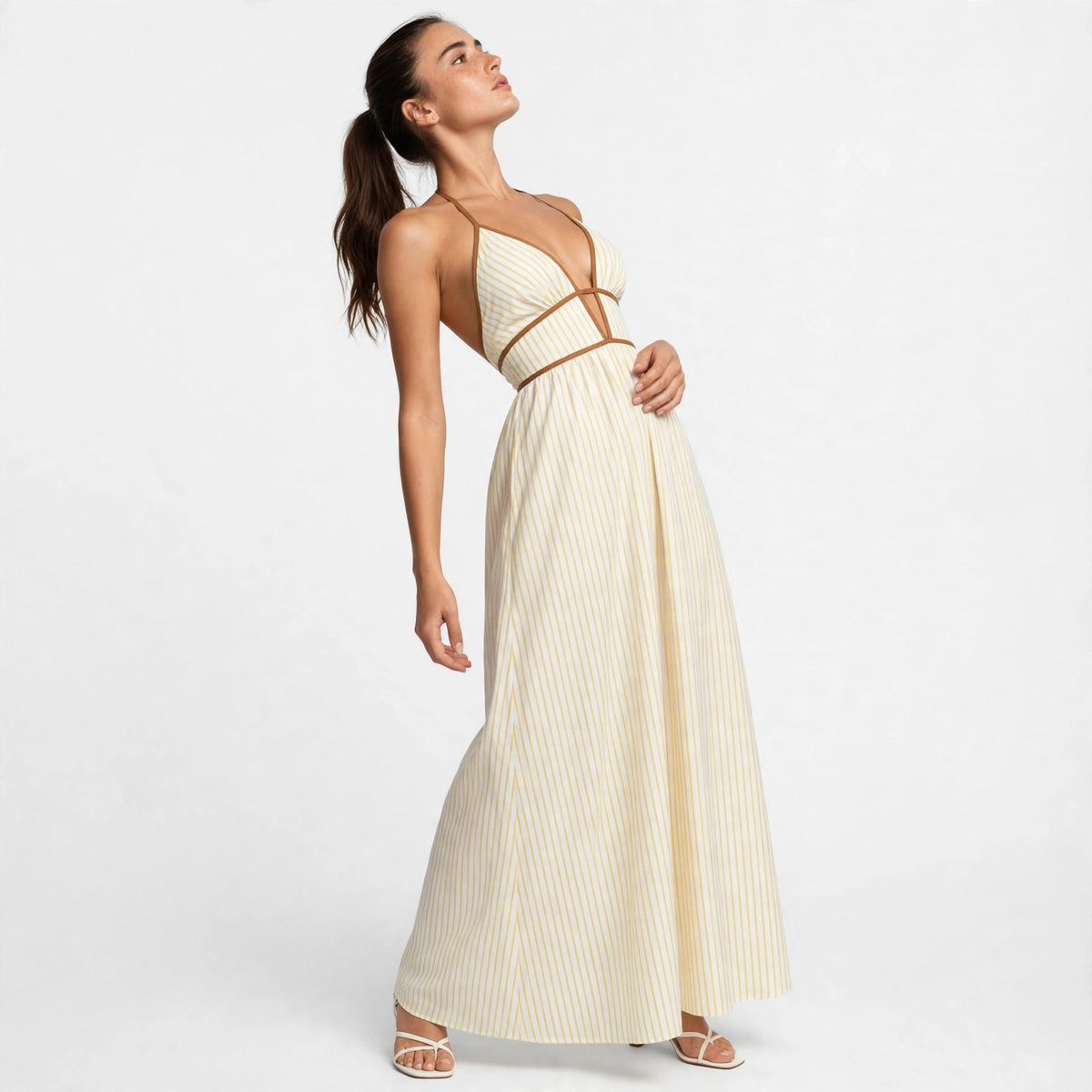Model posing in yellow striped smocked halter maxi dress, editorial front view