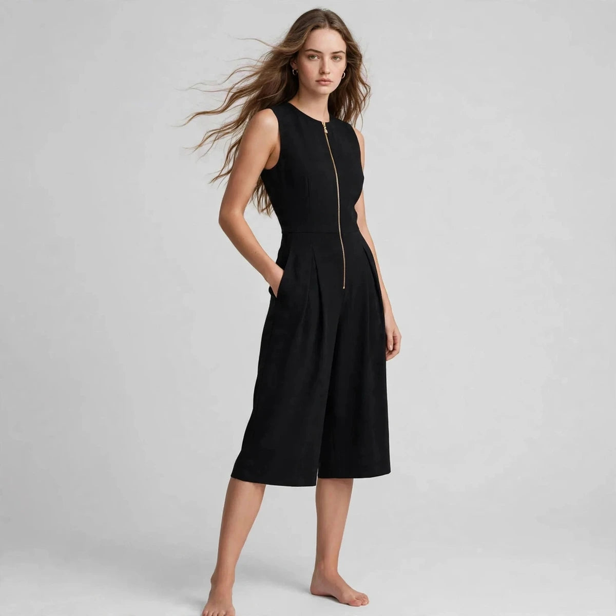 Three-quarter view of black sleeveless jumpsuit with front zipper and side pockets