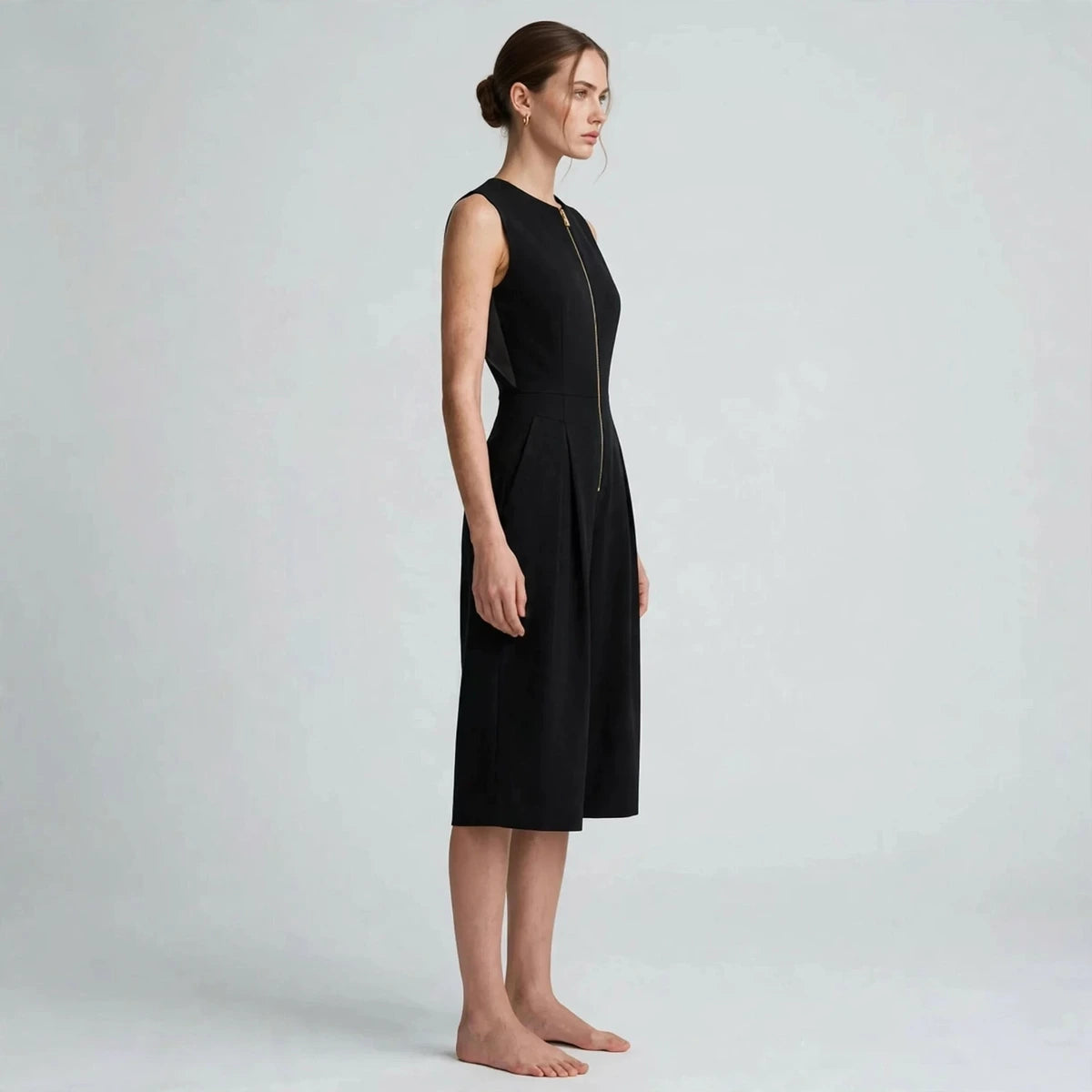 Side view of black sleeveless jumpsuit with exposed front zipper and cropped legs