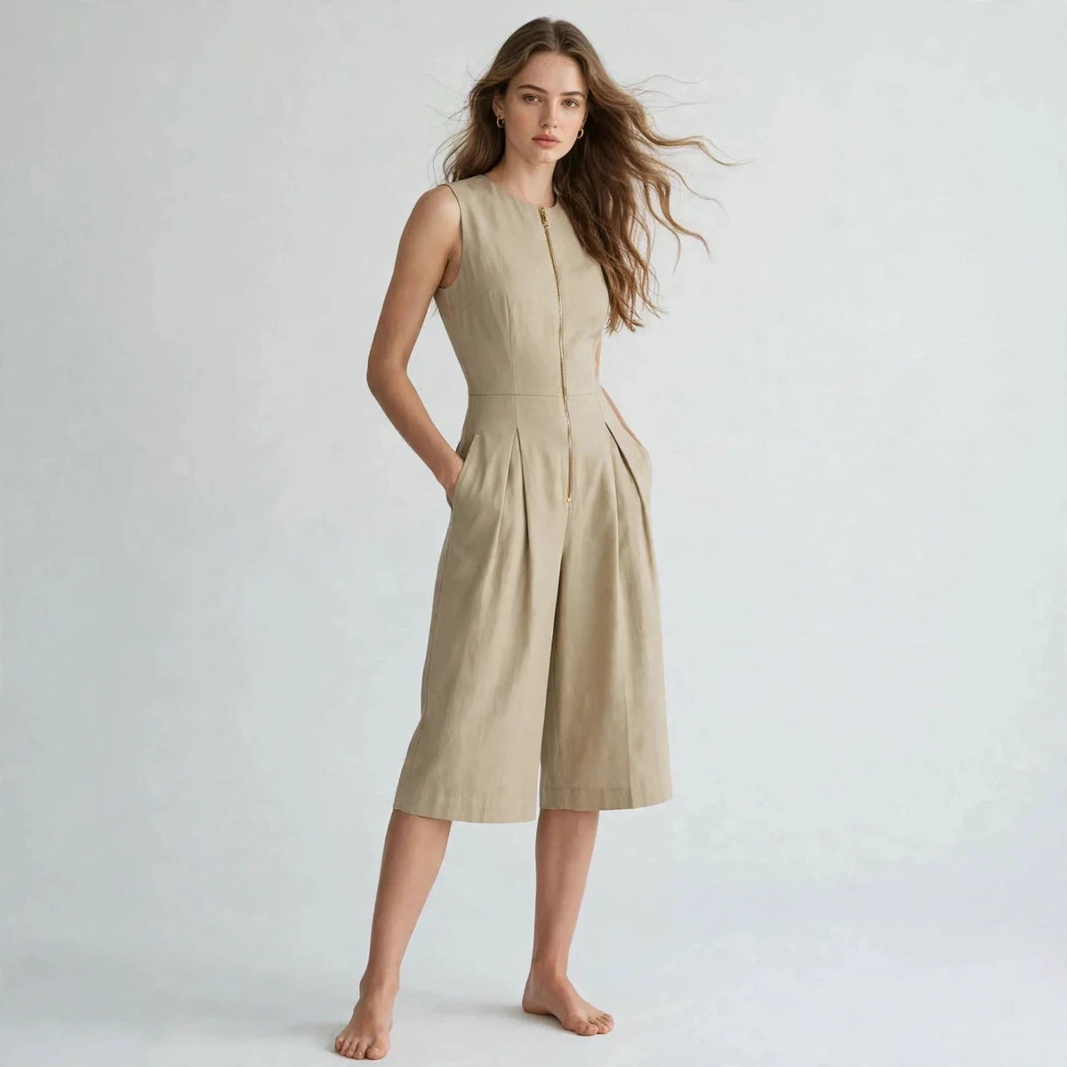Three-quarter view of khaki sleeveless zipper pocket jumpsuit with hands in pockets